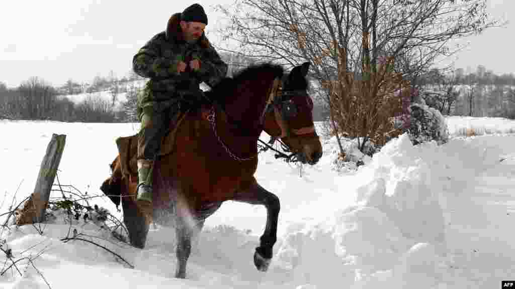 A man rides a horse through snow in the village of Vrapce, near the southern Serbian town of Medvedja, some 300 kilometers south of Belgrade.