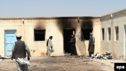 Men survey a school, allegedly burned by Taliban militants, in Kandahar.