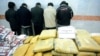 A pile of drugs is displayed in front of a group of suspected drug traffickers arrested in Iran.