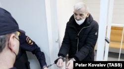 Yury Dmitriyev is led out of the court in Karelia in December 2021.