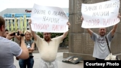 Journalist Sergei Duvanov and rights activist Andrei Sviridov hold signs on Almaty's main square