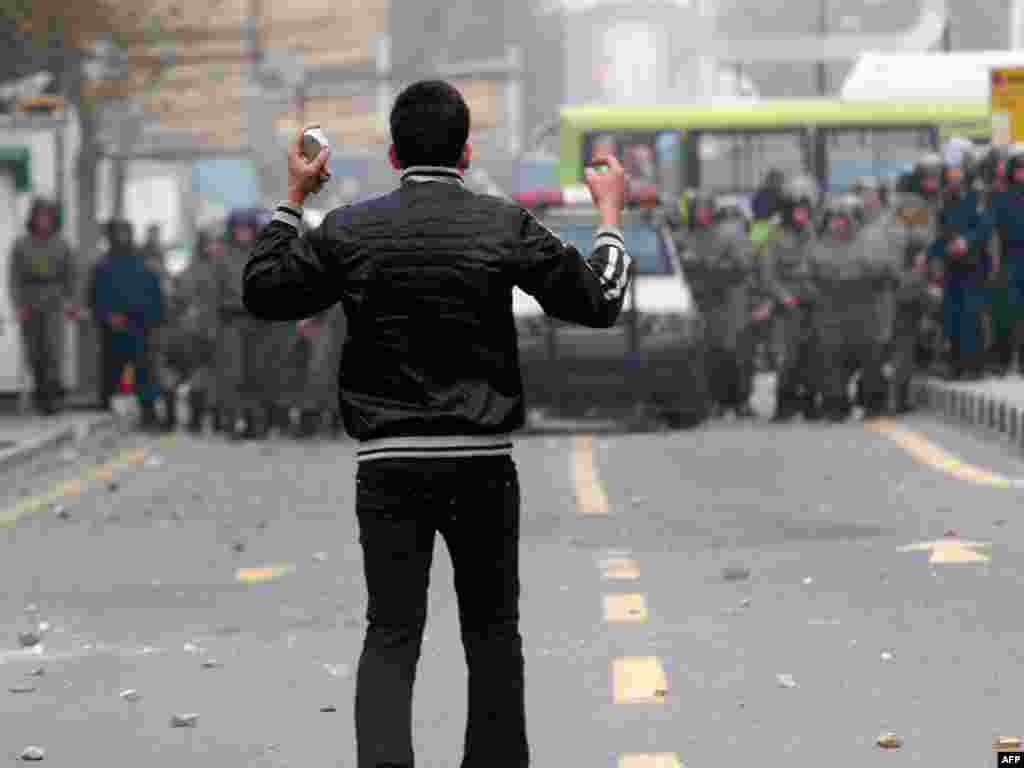 An opposition protester holds stones as he faces security forces. (AFP)