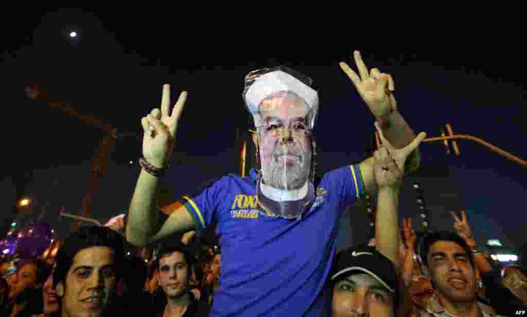 One of the celebrants at Vanak Square in Tehran wears a mask of the president-elect.