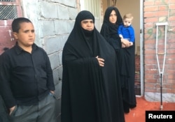 An Afghan refugee family stands outside a shelter in Iran's Kerman Province.