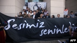 Supporters of world-renowned Turkish pianist Fazil Say stand behind a banner reading "Our voice is with you" during a protest held outside an Istanbul court, on October 18.