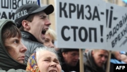 Ukrainian protesters hold up a sign reading "Stop the crisis!" in Kyiv. Berglof says there will be "several months of difficult time for Ukrainian companies and Ukrainian households."