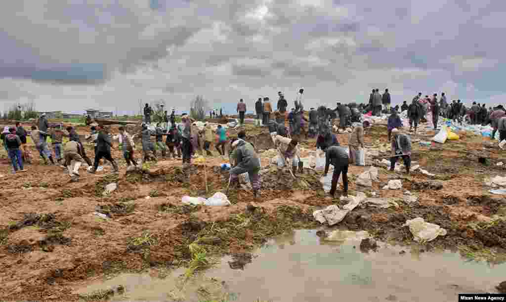 Rescue workers dig through the mud in Aq Qala.