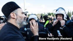 A Serbian Orthodox priest speaks with a riot policeman on a bridge near parliament, ahead of a vote on a bill on religious organizations in Podgorica on December 26.