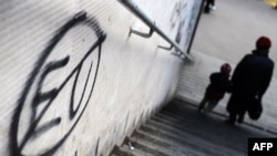 Pedestrians walk past anti-EU graffiti in downtown Belgrade.