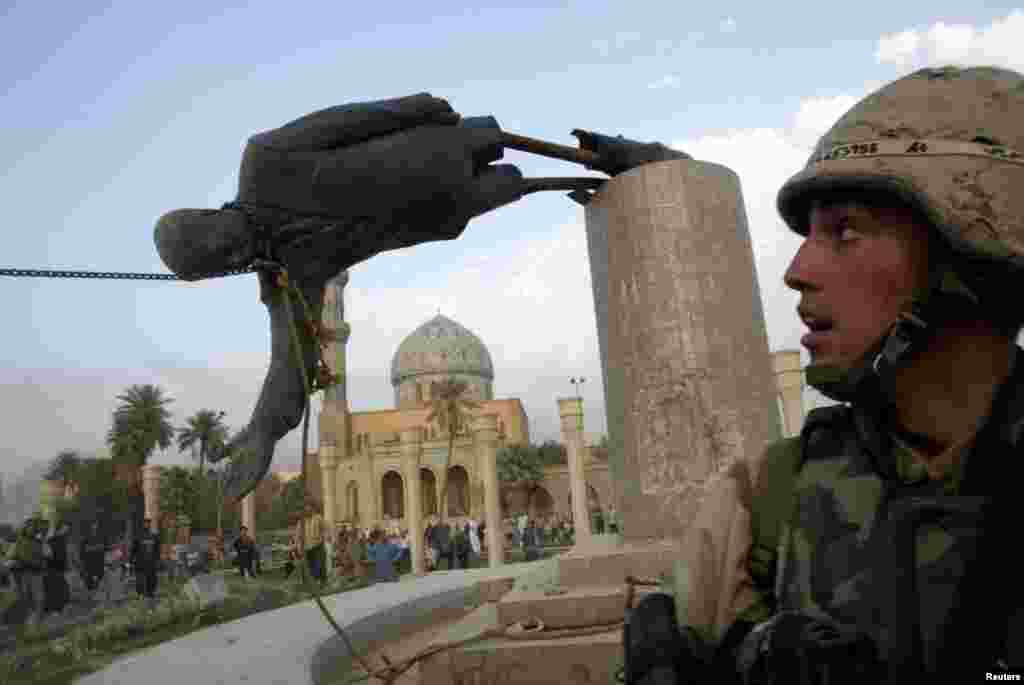 A U.S. Marine watches as a statue of Iraqi President Saddam Hussein falls in Firdos Square in Baghdad on April 9, 2003.