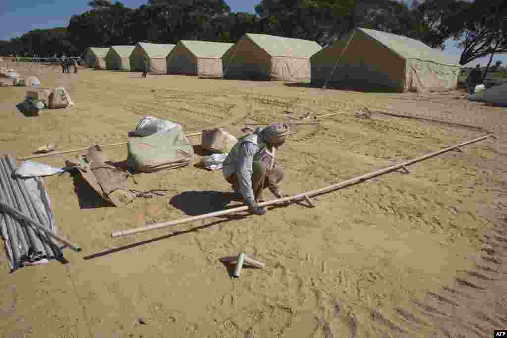 Red Crescent of the United Arab Emirates employees construct a new camp to shelter refugees who fled Libya in March 2011.