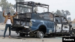 A protester stands next to the wreckage of an Iraqi police vehicle in Ramadi on December 30.