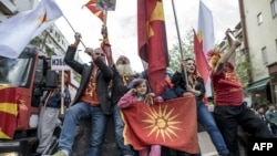 Macedonian protesters wave flags while riding an excavator during a demonstration against a deal to form a new government between the Social Democrats and ethnic Albanian parties. (file photo)