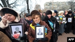 Widows of victims of the Chornobyl nuclear accident hold photos of their dead husbands at a ceremony at the Chornobyl memorial site in Kyiv.