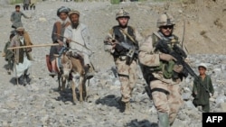 NATO-led International Security Assistance Force (ISAF) soldiers walk with villagers during a search for victims following an earthquake in Baghlan Province in June.