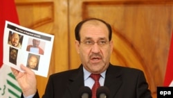 Iraqi Prime Minister Nuri al-Maliki displays photographs showing the body of Abu Omar al-Baghdadi during a news conference today.