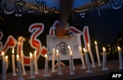 A Pakistani journalist holds a poster with a photo of a news cameraman killed in a suicide bombing in August 2016.