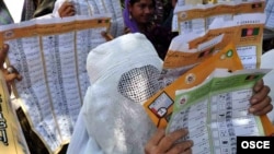 Women read mock ballots produced as part of a voter-education campaign ahead of the presidential and provincial elections in 2009.