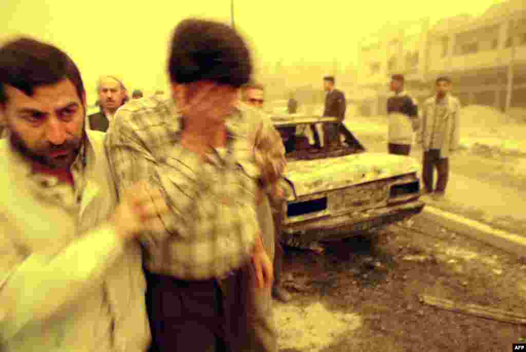 An Iraqi comforts a friend after missiles struck a Baghdad market, killing at least 14 people on March 26, 2003.