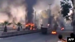 A video grab shows smoke billowing from burning tires and trash containers in the Al-Hajar Al-Aswad district of Damascus on July 18.