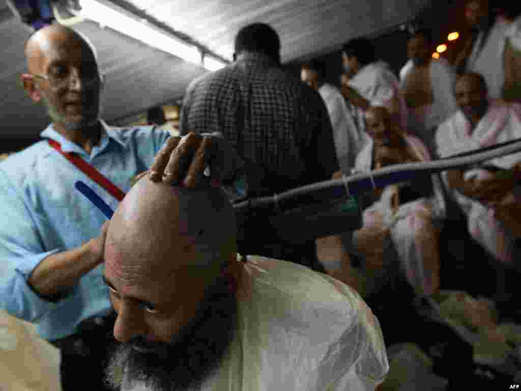 A barber in Mina shaves the head of a pilgrim after the stoning of Satan ritual. (AFP PHOTO/MAHMUD HAMS)