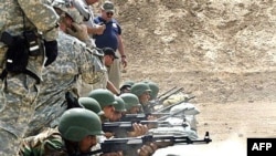 U.S. soldiers observe Iraqi police cadets shoot as they train at a firing range at a training base in the town of Hillah.