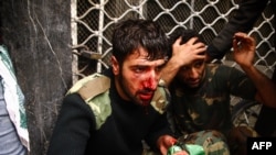 Injured Iranian security service members sit protected by opposition protesters in Tehran on December 27.