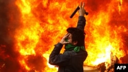 An opposition supporter stands near a police motorcycle set on fire during clashes with security forces in Tehran on December 27.