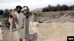 Afghan men show pieces of missiles that they say struck their village in Farah Province.