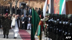 Transition Commission Chairman Ashraf Ghani Ahmadzai (second from left) and Afghan Defense Minister Abdul Rahim Wardak (far left) inspect an honor guard during a ceremony to assume security control in the city of Charikar in Parwan Province on December 1.