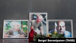 Photographs of journalists Orkhan Dzhemal (right), Kirill Radchenko (center) and Aleksandr Rastorguyev are seen at a small memorial to the slain jounalists outside the Central House of Journalists in Moscow.