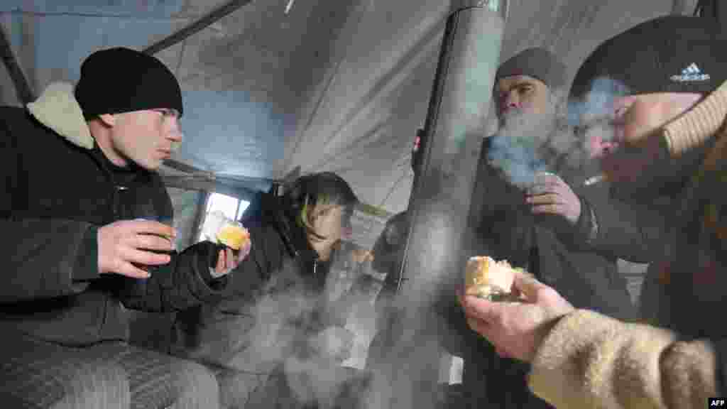 Homeless people eat a hot meal and drink tea in one of the newly opened tent shelters in the western Ukrainian city of Lviv.