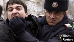 A policeman detains an opposition activist in Baku. The report says Azerbaijan's government unleashed a "new wave of repression and intimidation" in the past year.