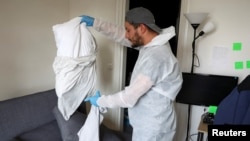 A biocide technician removes pillowcases to prevent the alleged spread of bedbugs in an apartment in L'Hay-les-Roses, near Paris, in September 2023. 