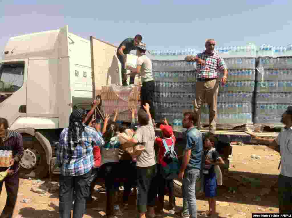 Refugees receive food and water in the border village of Sihela, in Iraq&#39;s autonomous Kurdish region. 