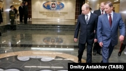 President Vladimir Putin and then Defense Minister Sergei Ivanov cast sidelong glances at the traditional GRU logo. (file photo)