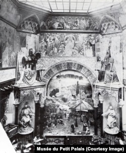 The interior of the Bosnian pavilion after it opened to the public. Beneath the archway, a painting of a Sarajevo marketplace rises above some carpets.