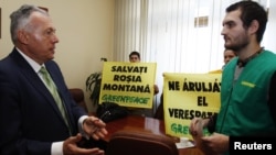 Romanian Environment Minister Laszlo Borbely (left) talks to a Greenpeace activist while others hold banners reading "Save Rosia Montana" in his office in central Bucharest on January 31.