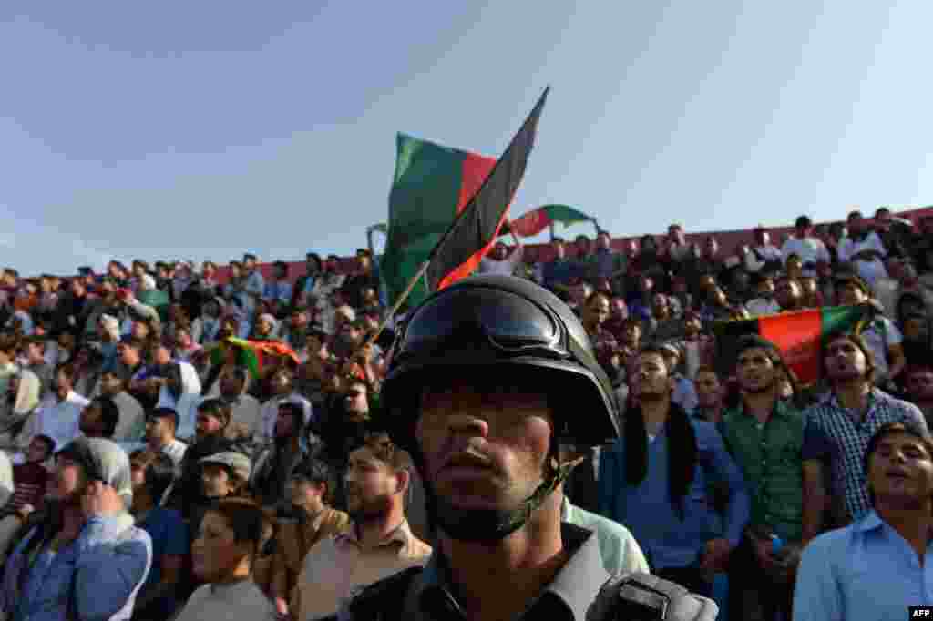 An Afghan policeman keeps watch as spectators watch the game.