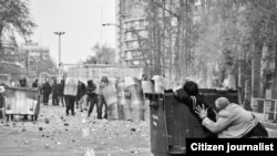 Two men hide from riot policemen behind a trash bin during clashes in Tehran on December 27.