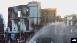 Firefighters douse a burnt out building following following a night of violence on the streets of London.