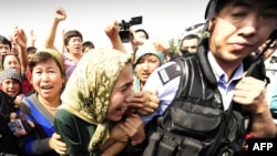 Ethnic Uyghur women grab at a riot policeman as they protest in Urumqi, Xinjiang province, on July 7.