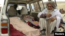 An elderly man sits next to the covered bodies of Afghans killed after what is believed to have been a shooting rampage by a U.S. soldier in Kandahar Province on March 11.