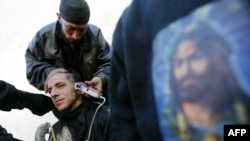 A Shi'a in Karbala has his head shaved alongside an image of Imam Hussein on the eve of Ashura.