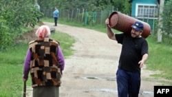 A Belarusian man carries a gas cylinder in the village of Krasnoe on June 22.