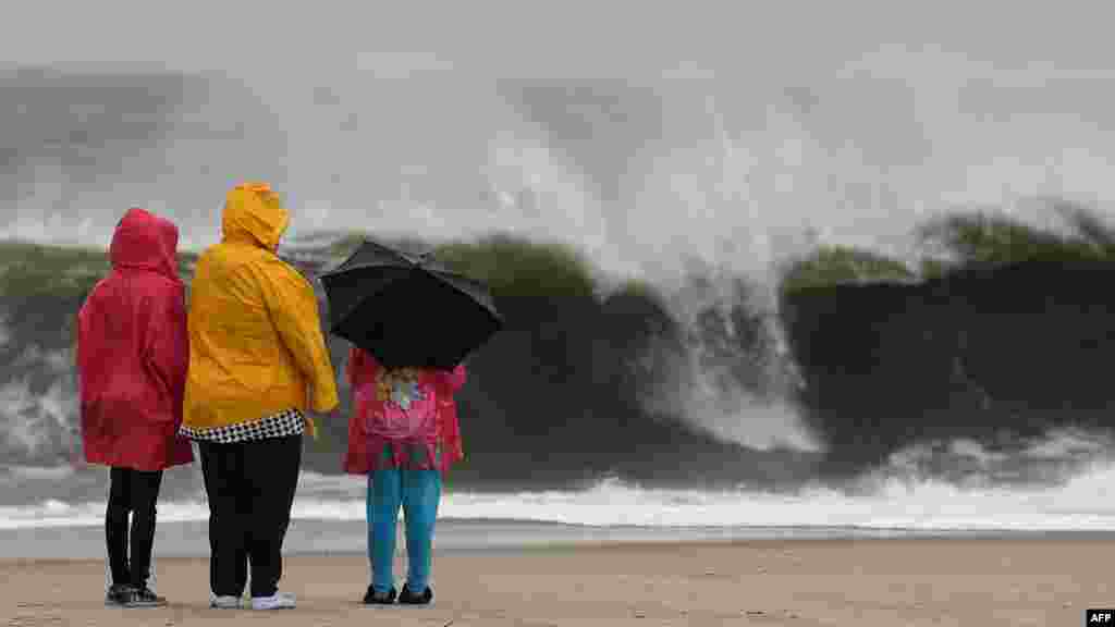 People stand on the beach watching the heavy surf caused by the approaching Hurricane Sandy, Cape May, New Jersey.