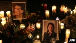 Candles surround portraits of federal Judge John Roll and Representative Gabrielle Giffords. Roll was killed in the shooting; Giffords is in critical condition.