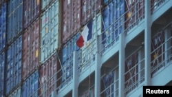 A French flag flies next to containers on a cargo ship owned by shipping company CMA CGM.