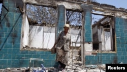 A woman searches for usable objects in a house burnt down during ethnic clashes in the city of Osh in June 2010.