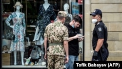 Azerbaijani security officers wearing protective face masks check the documents of a man in Baku. (file photo)